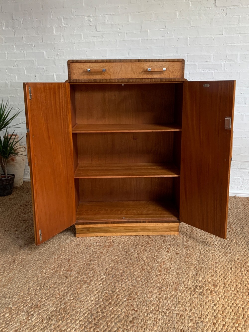 An Art Deco tallboy made from book-matched burr walnut, featuring a top drawer over a two-door cabinet on a stepped plinth base. View II