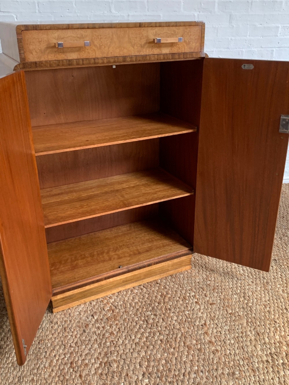 An Art Deco tallboy made from book-matched burr walnut, featuring a top drawer over a two-door cabinet on a stepped plinth base. View III