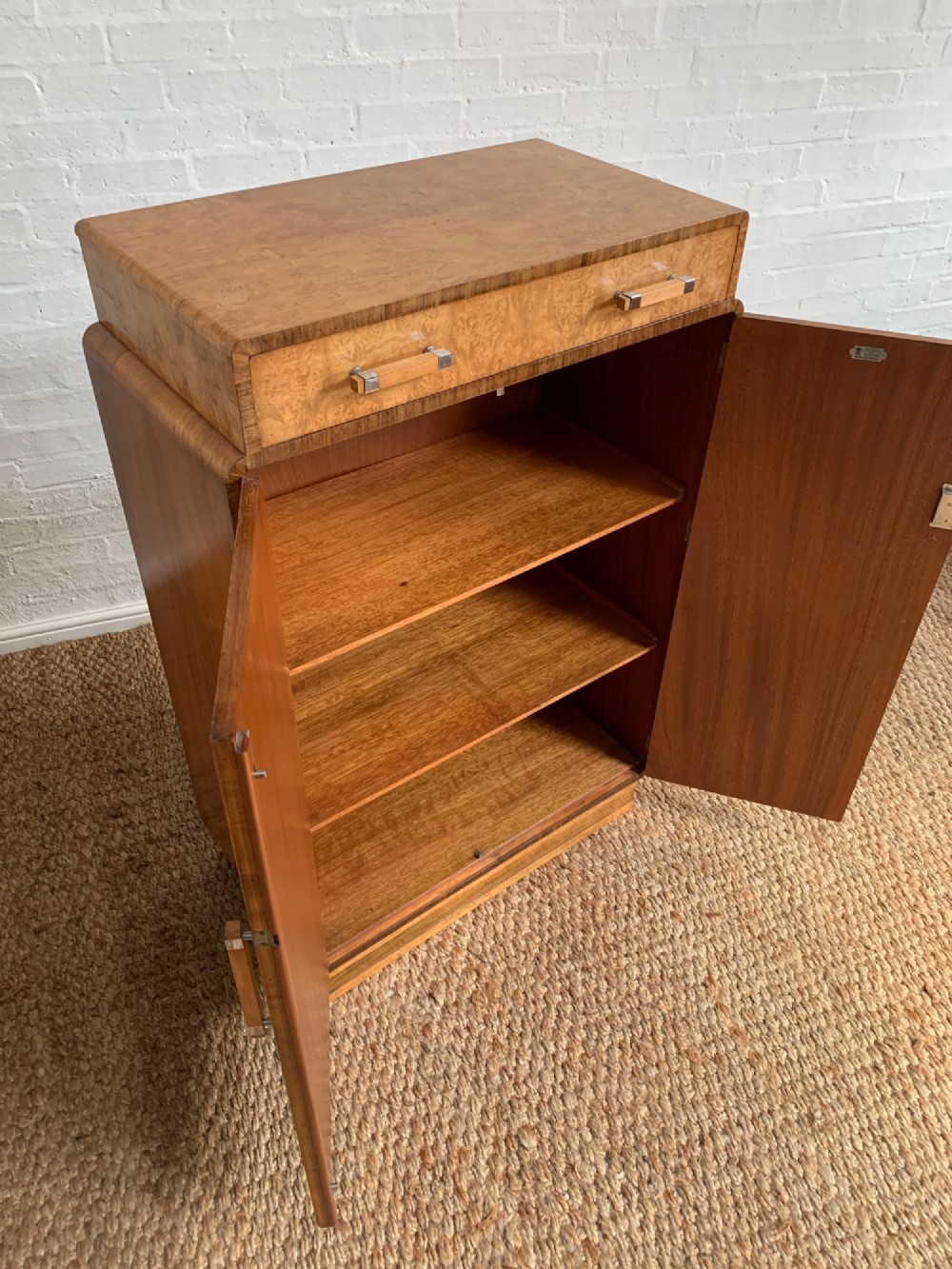 An Art Deco tallboy made from book-matched burr walnut, featuring a top drawer over a two-door cabinet on a stepped plinth base. View IV