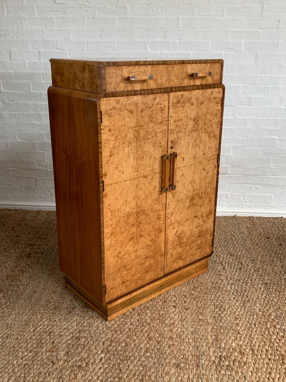 An Art Deco tallboy made from book-matched burr walnut, featuring a top drawer over a two-door cabinet on a stepped plinth base. View VII
