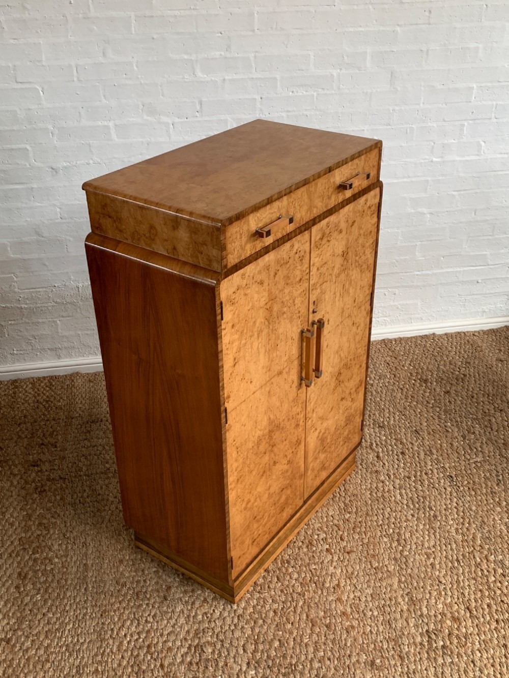 An Art Deco tallboy made from book-matched burr walnut, featuring a top drawer over a two-door cabinet on a stepped plinth base. View VIII