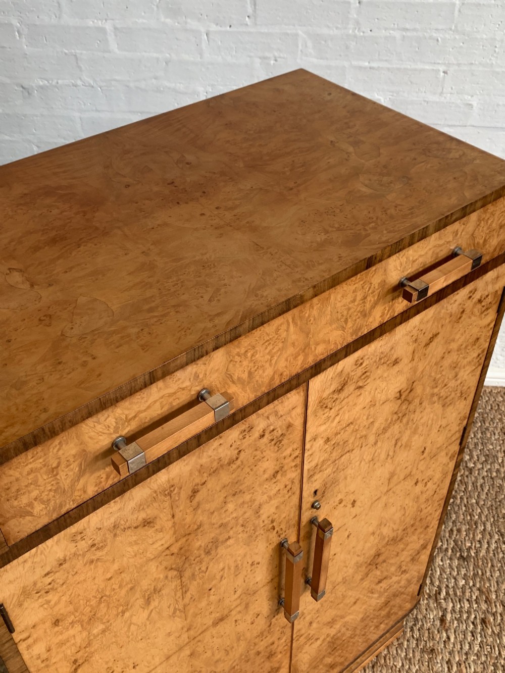An Art Deco tallboy made from book-matched burr walnut, featuring a top drawer over a two-door cabinet on a stepped plinth base. View IX