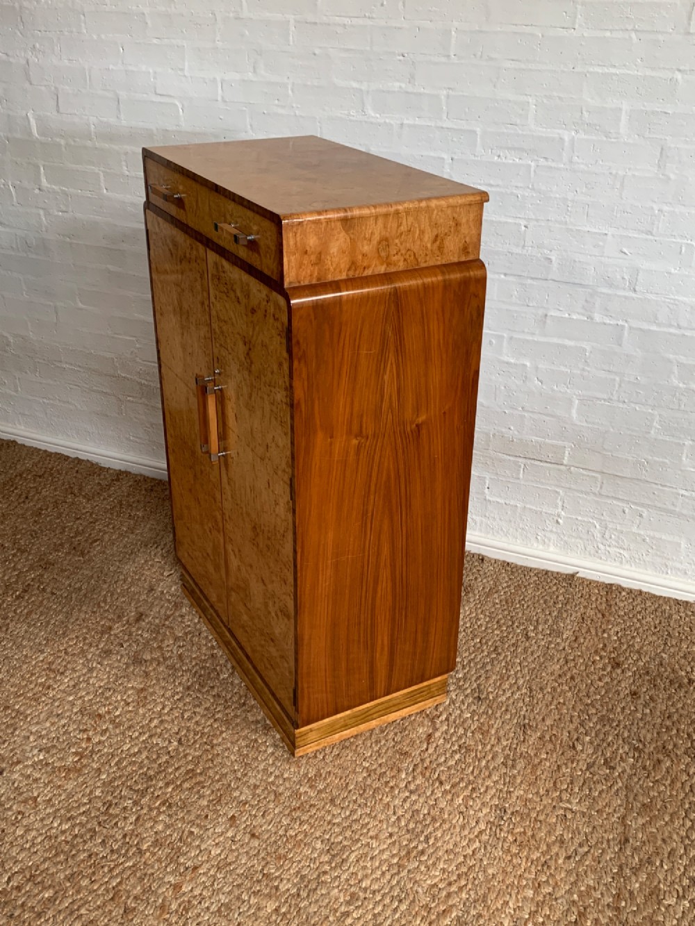An Art Deco tallboy made from book-matched burr walnut, featuring a top drawer over a two-door cabinet on a stepped plinth base. View XI