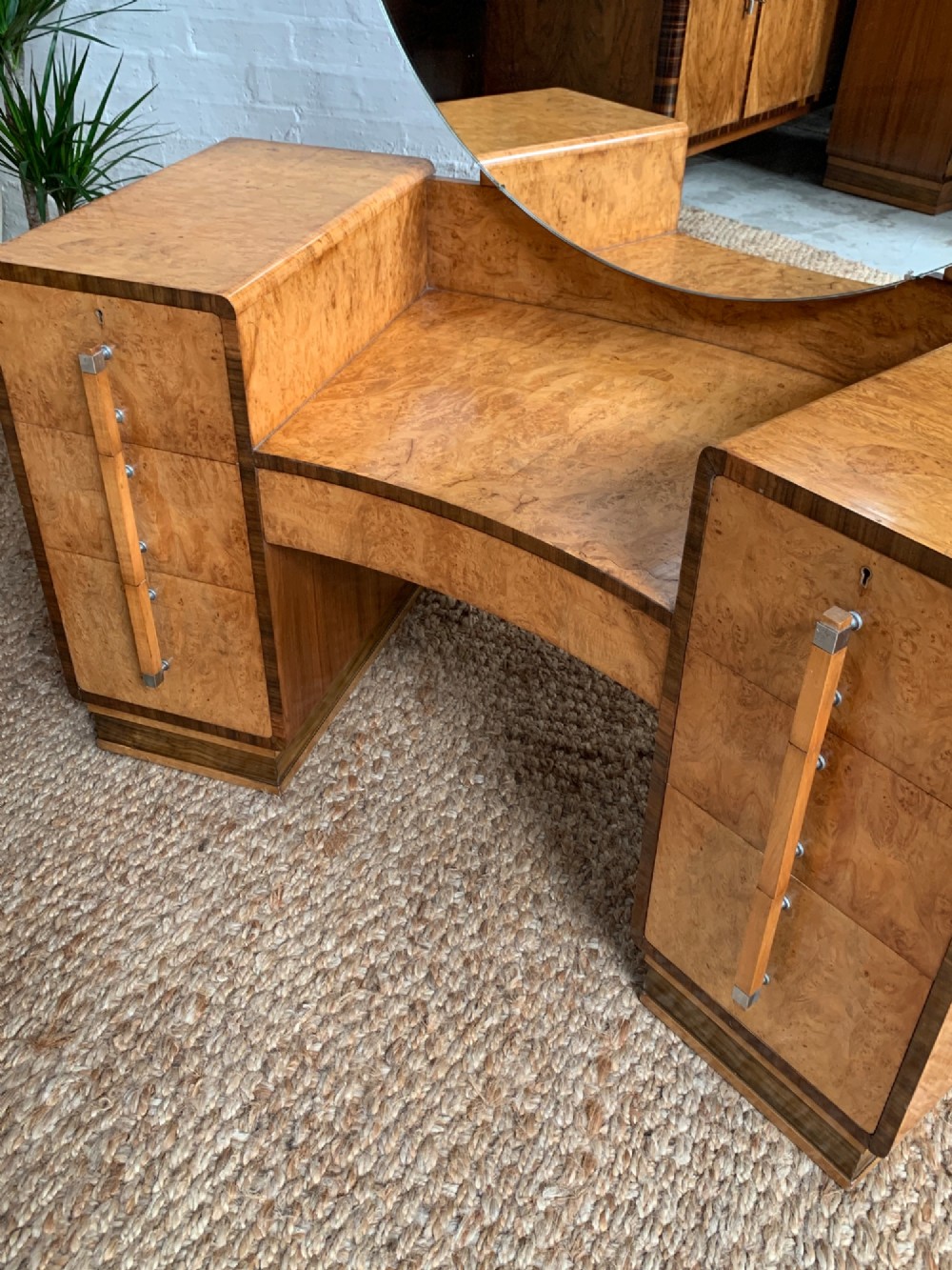 An Art Deco burr walnut dressing table featuring a circular mirror, twin pedestals, and vertical drawer handles. View VII