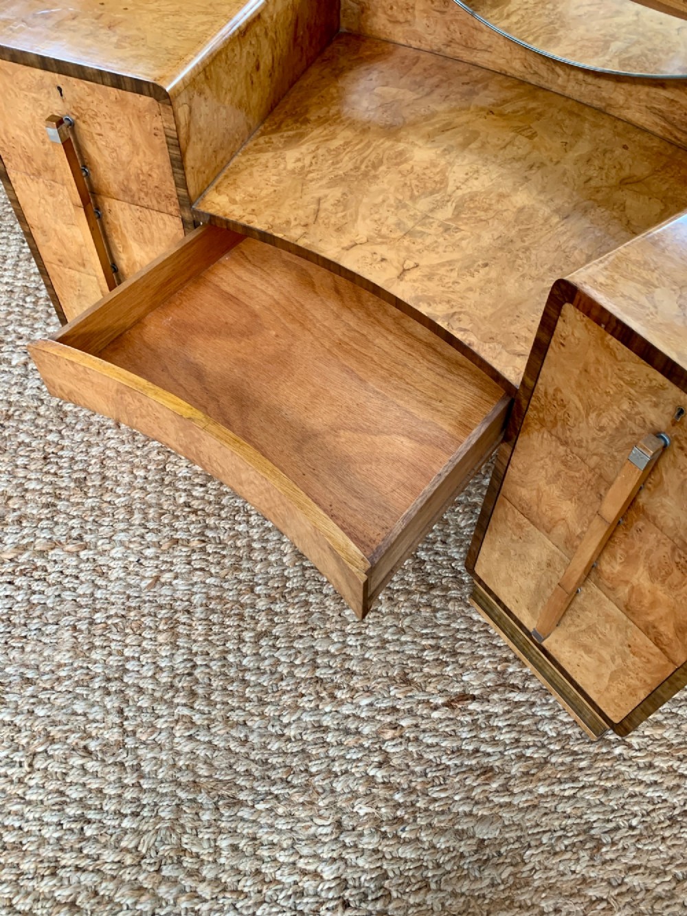 An Art Deco burr walnut dressing table featuring a circular mirror, twin pedestals, and vertical drawer handles. View XII
