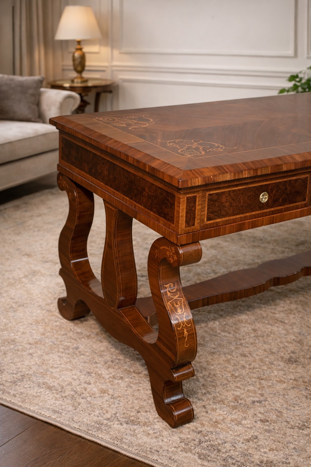 A rectangular walnut writing desk featuring decorative corner marquetry, three frieze drawers with brass pulls, curved lyre-shaped legs, and a shaped central stretcher. View II