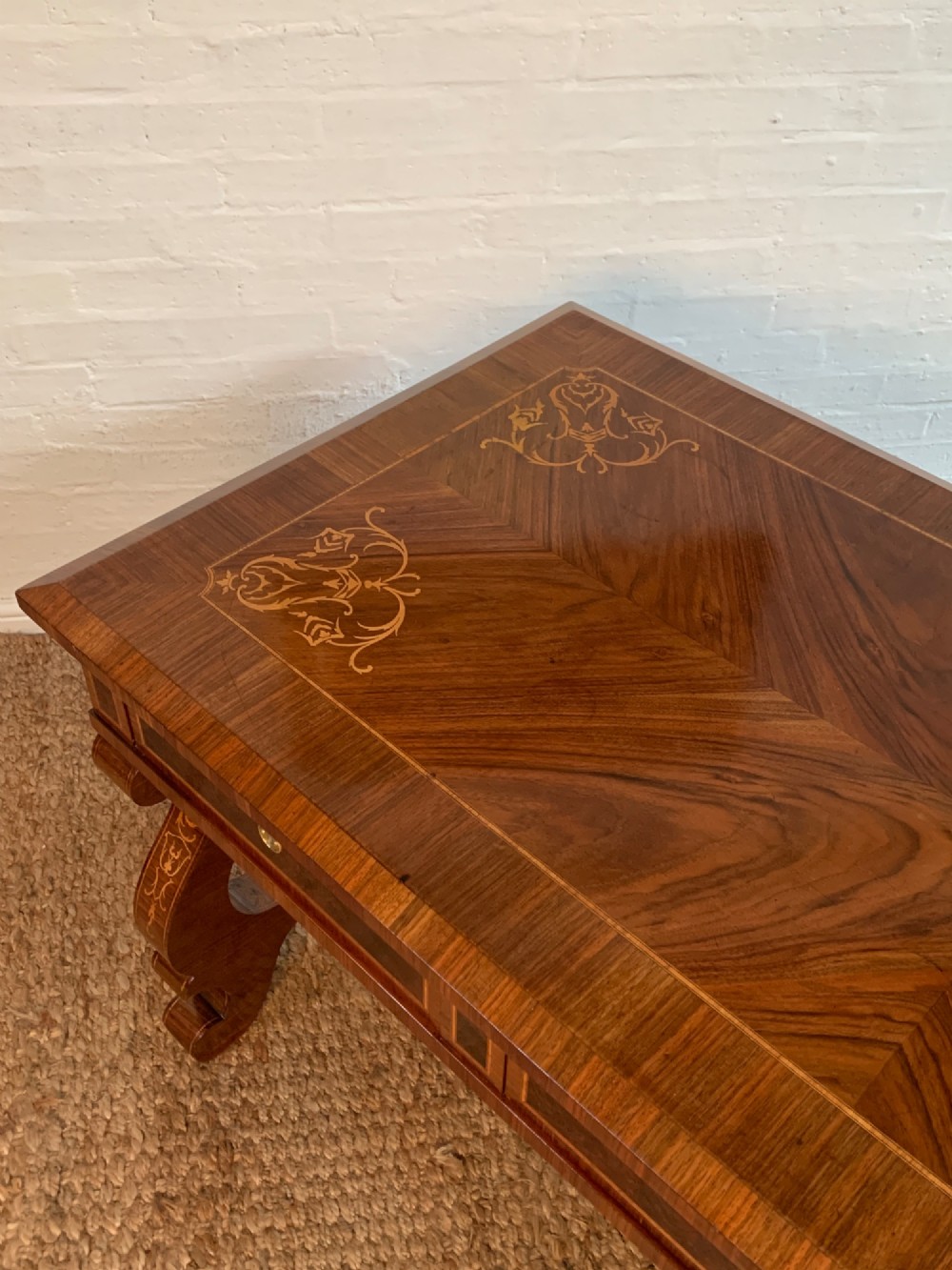 A rectangular walnut writing desk featuring decorative corner marquetry, three frieze drawers with brass pulls, curved lyre-shaped legs, and a shaped central stretcher. View IV