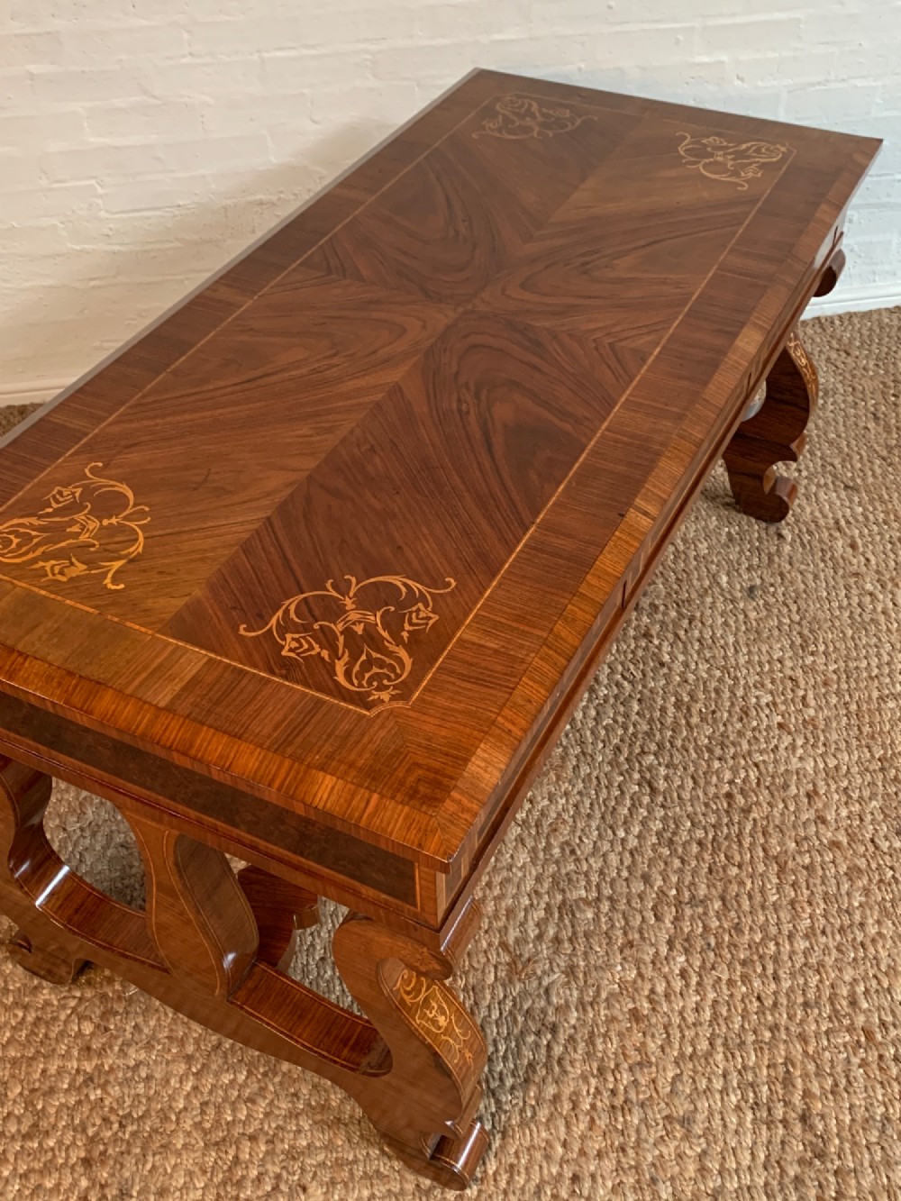 A rectangular walnut writing desk featuring decorative corner marquetry, three frieze drawers with brass pulls, curved lyre-shaped legs, and a shaped central stretcher. View IX