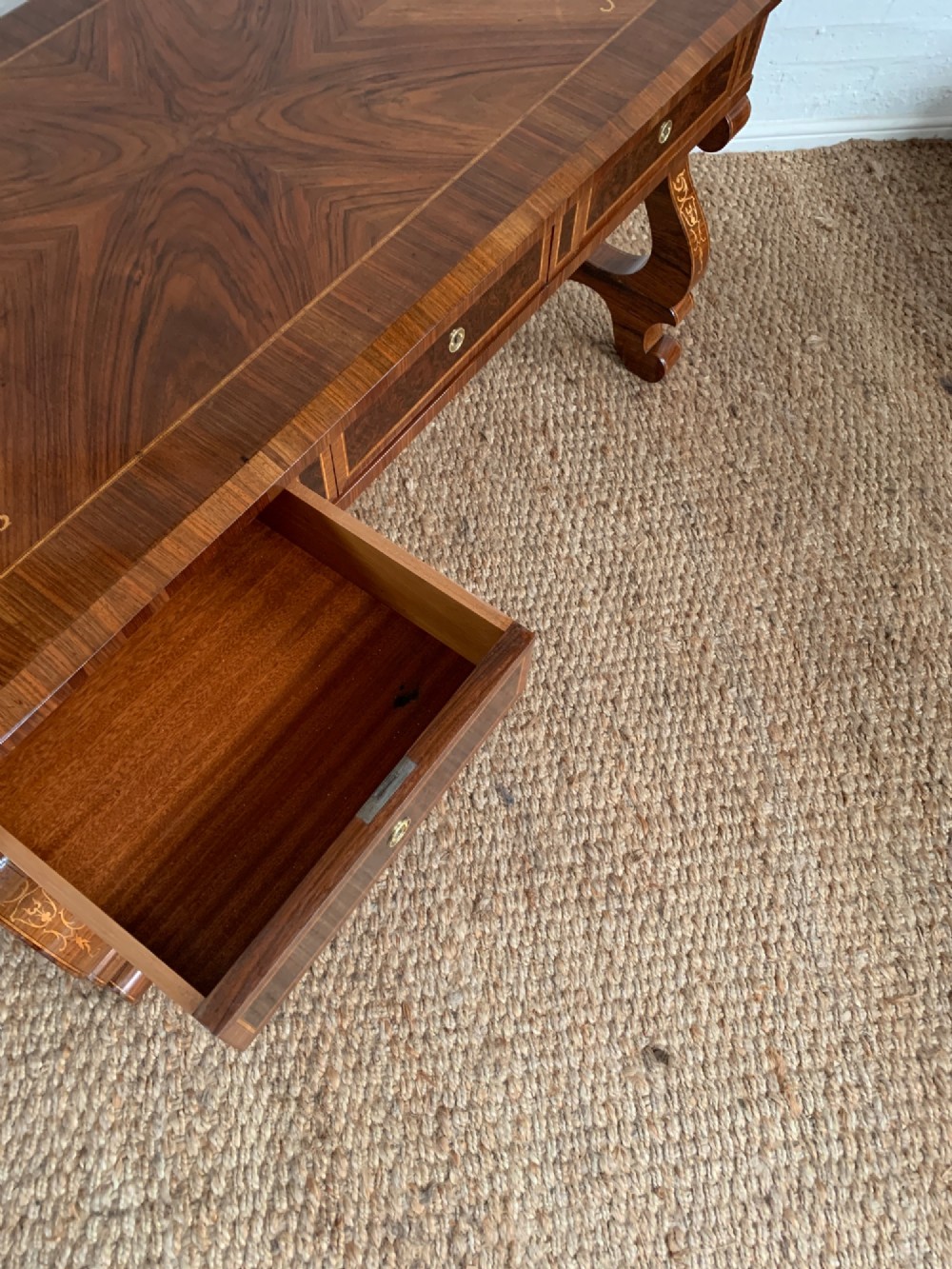 A rectangular walnut writing desk featuring decorative corner marquetry, three frieze drawers with brass pulls, curved lyre-shaped legs, and a shaped central stretcher. View XI