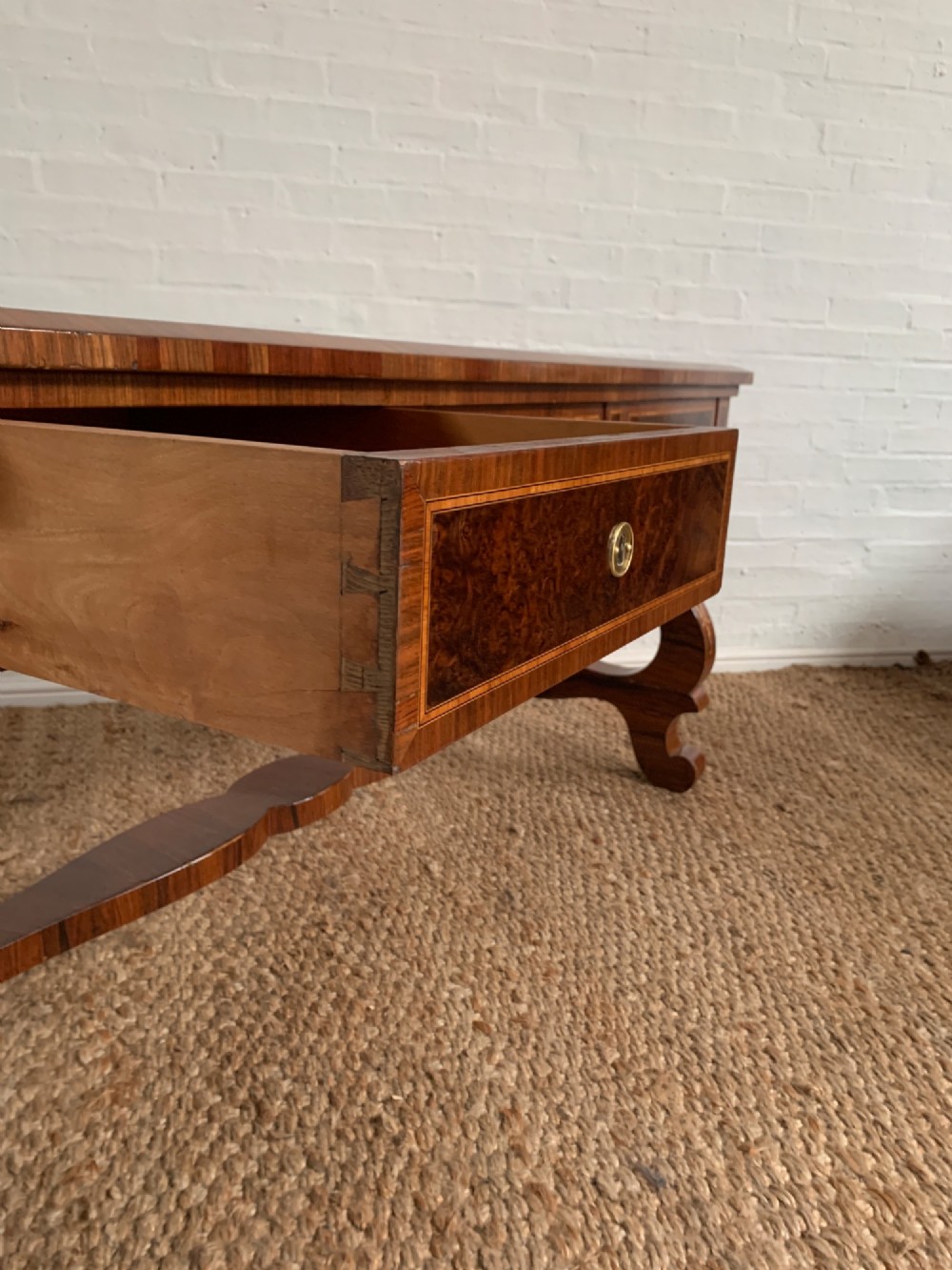 A rectangular walnut writing desk featuring decorative corner marquetry, three frieze drawers with brass pulls, curved lyre-shaped legs, and a shaped central stretcher. View XII