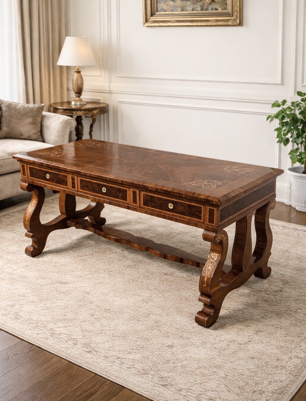 A rectangular walnut writing desk featuring decorative corner marquetry, three frieze drawers with brass pulls, curved lyre-shaped legs, and a shaped central stretcher.