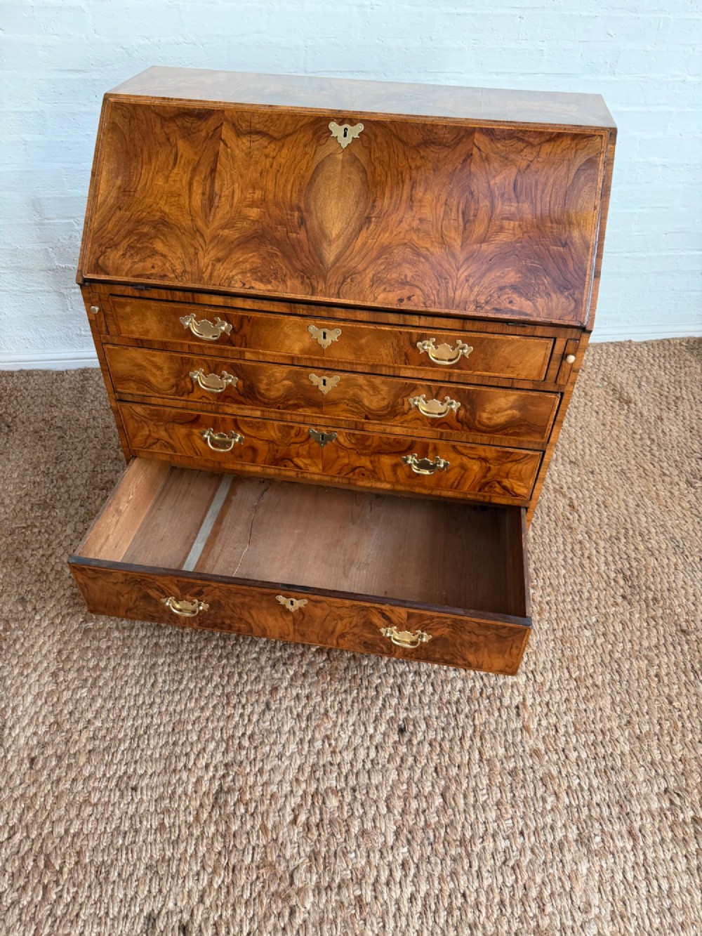 A Georgian period figured walnut bureau featuring a slant front flap above four graduated drawers with brass handles, resting on bracket feet. View V