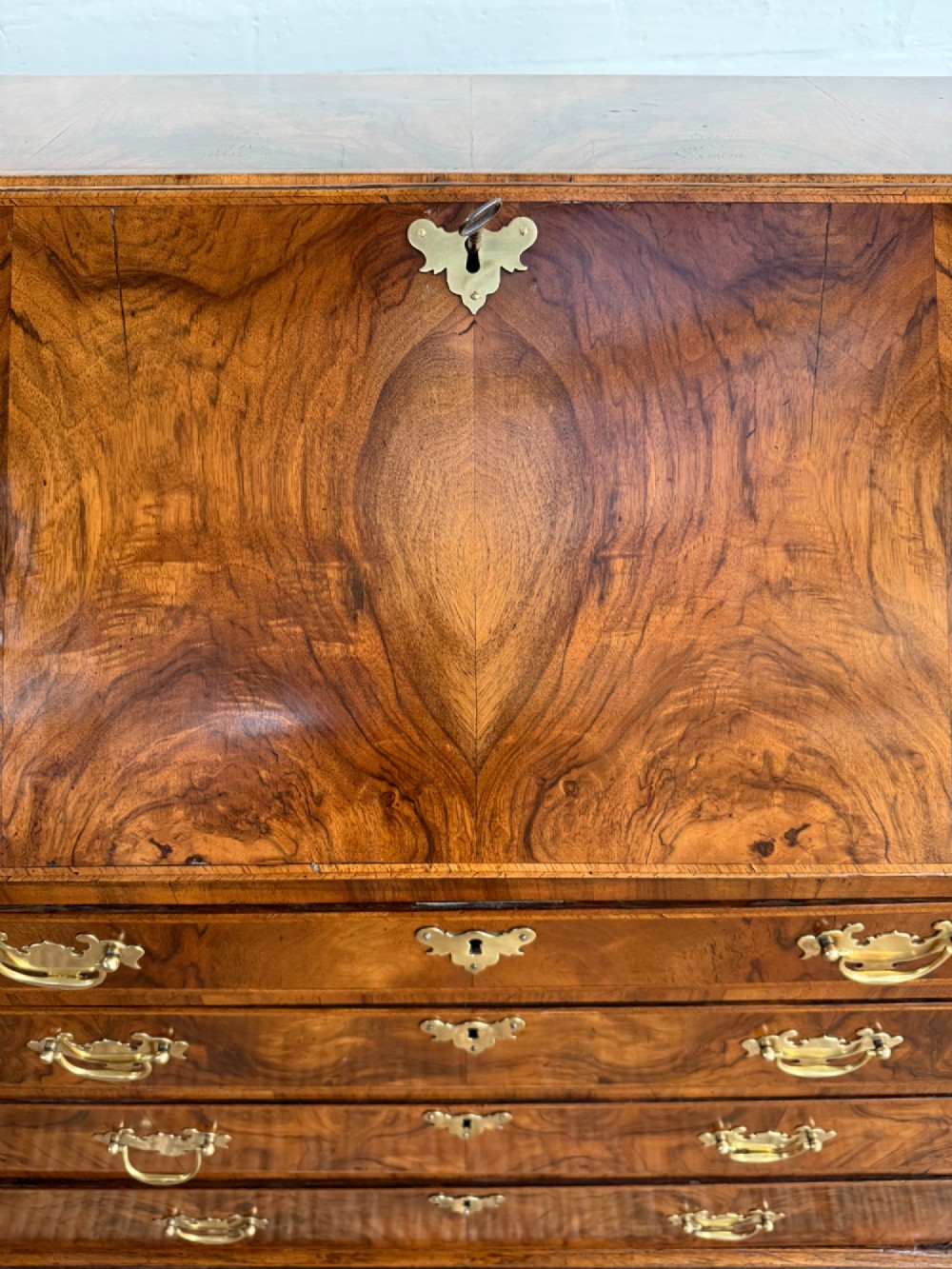A Georgian period figured walnut bureau featuring a slant front flap above four graduated drawers with brass handles, resting on bracket feet. View VII