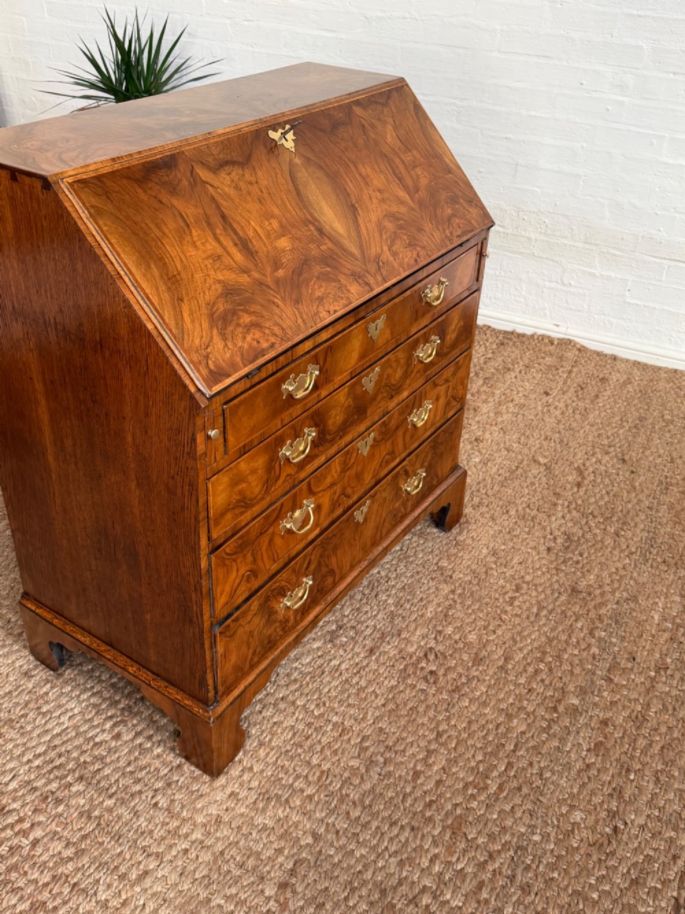 A Georgian period figured walnut bureau featuring a slant front flap above four graduated drawers with brass handles, resting on bracket feet. View X