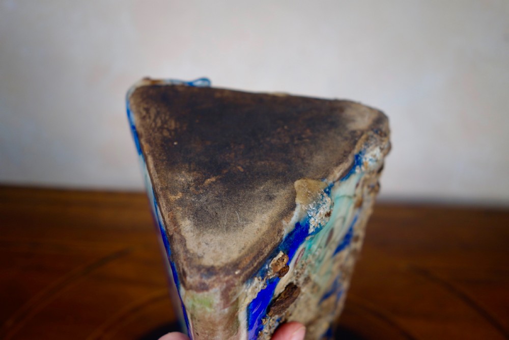 A triangular Persian glazed earthenware vessel decorated with cobalt blue, turquoise, and hand-painted arabesque motifs along its sides. View III