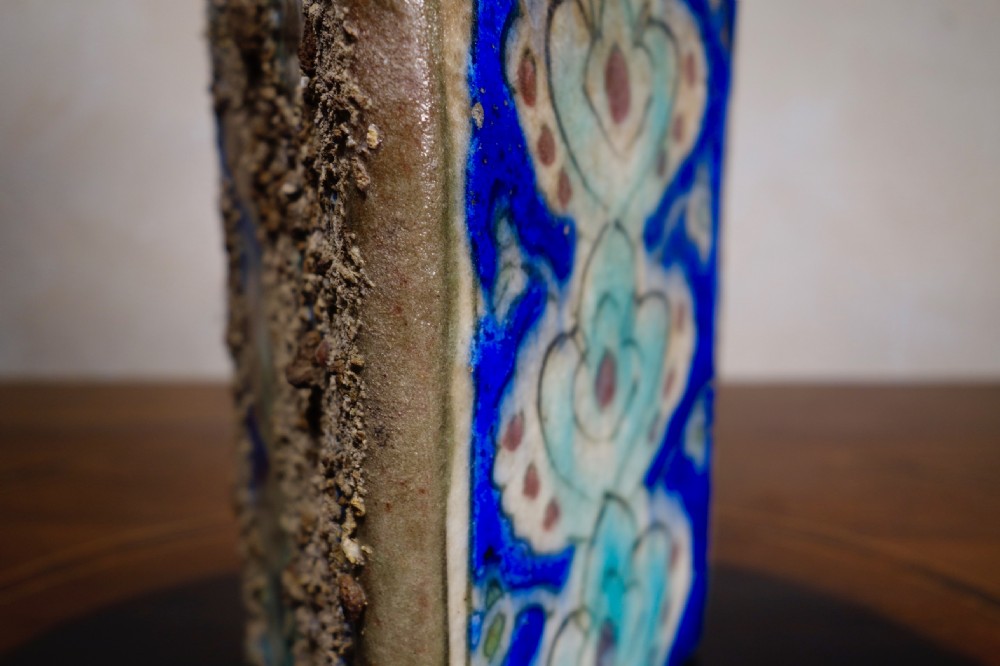 A triangular Persian glazed earthenware vessel decorated with cobalt blue, turquoise, and hand-painted arabesque motifs along its sides. View IV