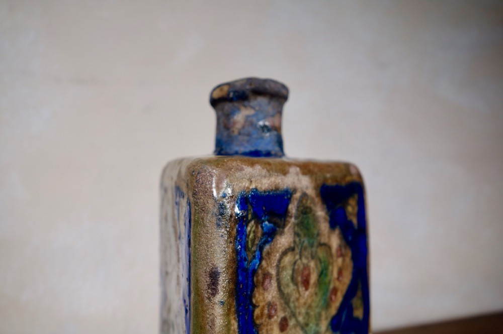 A triangular Persian glazed earthenware vessel decorated with cobalt blue, turquoise, and hand-painted arabesque motifs along its sides. View VII