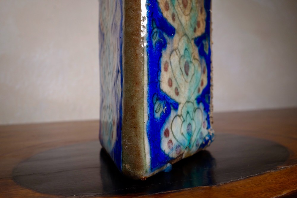 A triangular Persian glazed earthenware vessel decorated with cobalt blue, turquoise, and hand-painted arabesque motifs along its sides. View XI