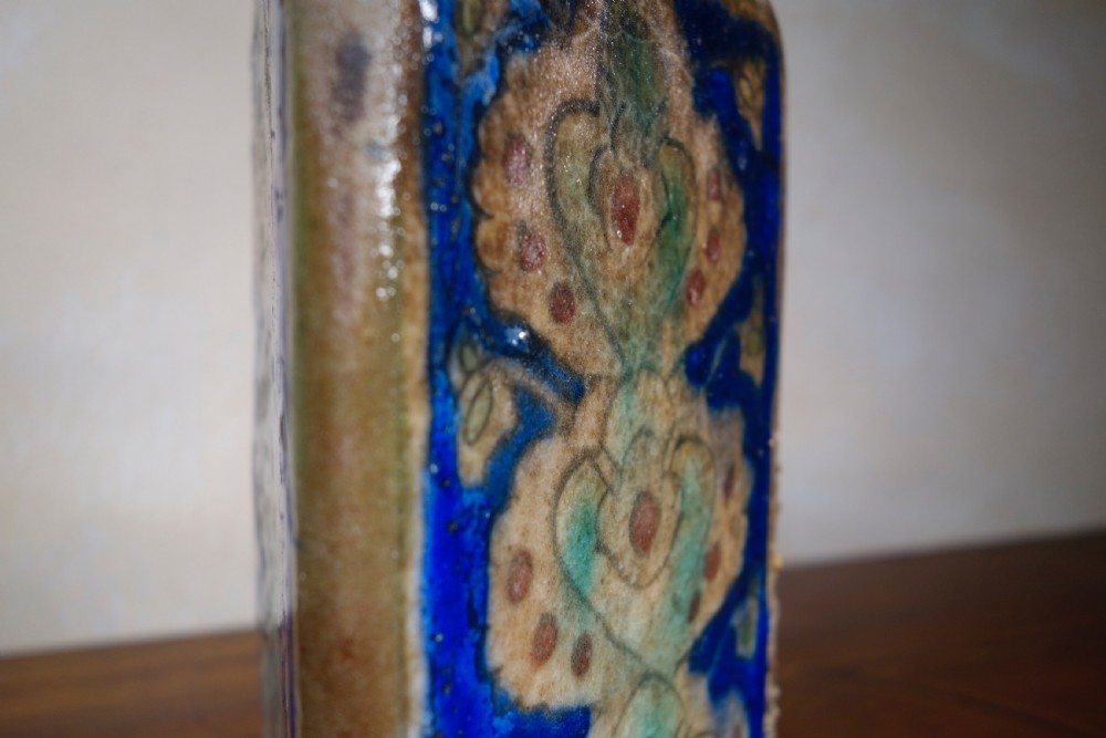 A triangular Persian glazed earthenware vessel decorated with cobalt blue, turquoise, and hand-painted arabesque motifs along its sides. View XII