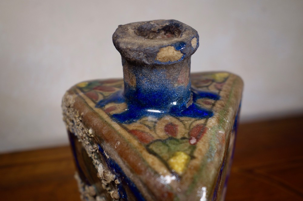 A triangular Persian glazed earthenware vessel decorated with cobalt blue, turquoise, and hand-painted arabesque motifs along its sides. View XIII