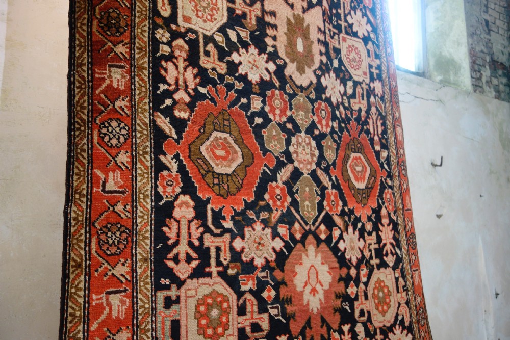 A long 19th-century Caucasian Kuba kelleh corridor runner rug featuring geometric medallions on a dark blue field framed by a terracotta border. View II