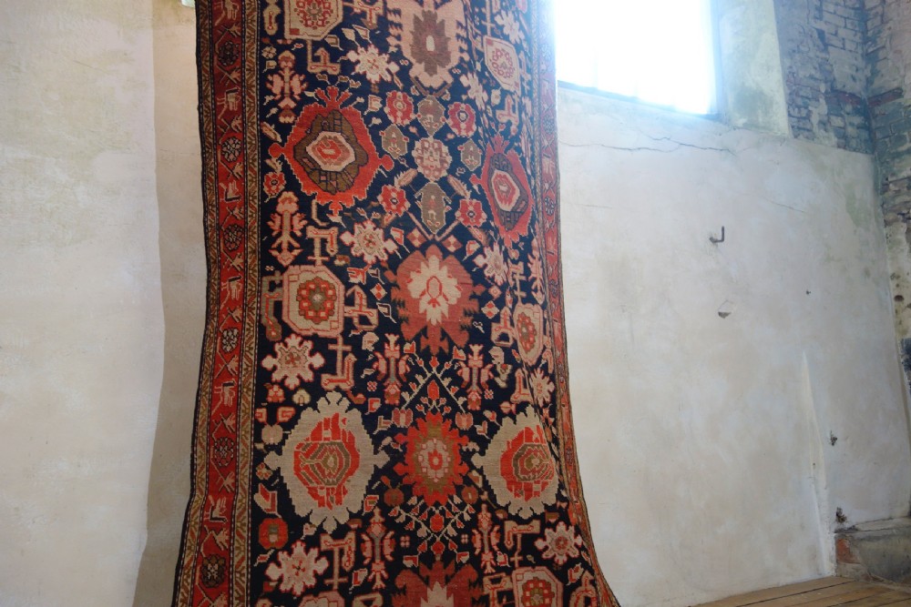 A long 19th-century Caucasian Kuba kelleh corridor runner rug featuring geometric medallions on a dark blue field framed by a terracotta border. View IX