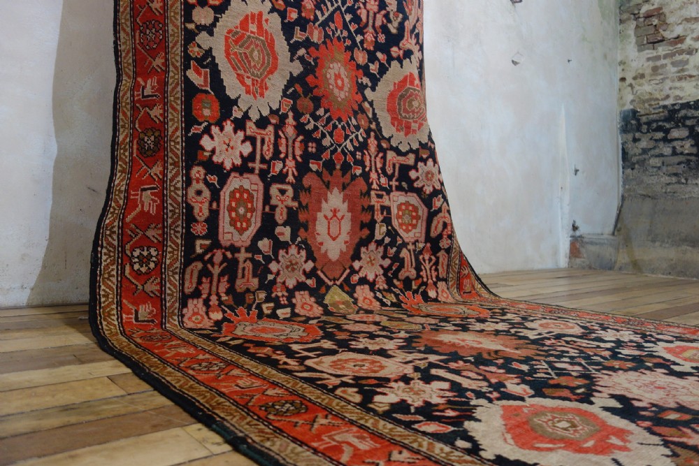 A long 19th-century Caucasian Kuba kelleh corridor runner rug featuring geometric medallions on a dark blue field framed by a terracotta border. View X