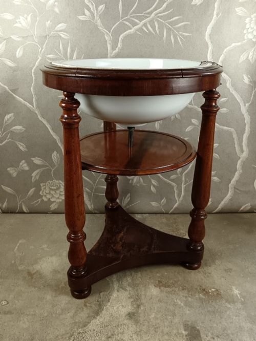 fig 1. A 19th-century circular mahogany campaign washstand featuring three turned legs, a circular tier, a triangular platform base, and an inset white ceramic wash basin.