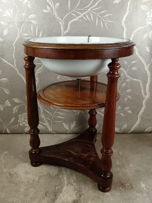 fig 2. A 19th-century circular mahogany campaign washstand featuring three turned legs, a circular tier, a triangular platform base, and an inset white ceramic wash basin.
