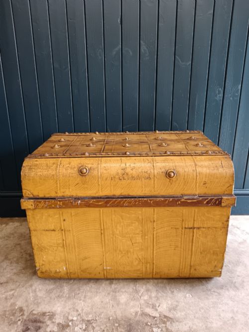 fig 2. A late nineteenth-century metal steamer trunk featuring a hand-painted faux wood grain finish, dark metal banding, studs, and a central latch.