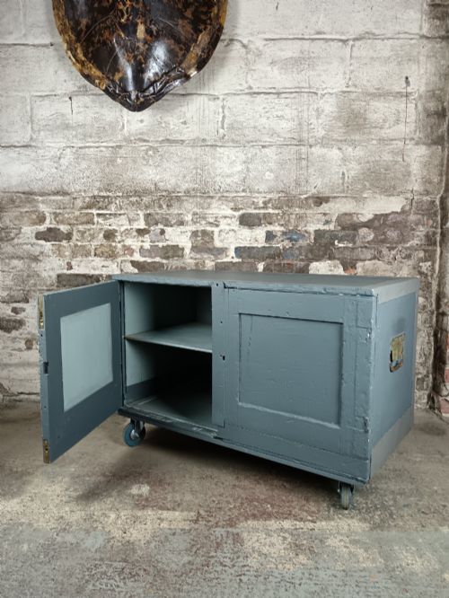 fig 1. A 19th-century wooden military transport packing case featuring a slate grey painted finish and panelled front doors set on castors.