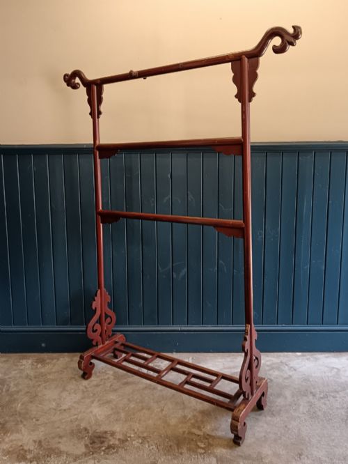 fig 2. A late 19th-century Chinese red lacquered wooden robe stand with carved scroll terminals, horizontal crossbars, and a lower latticework base.