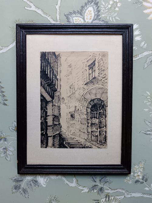 fig 1. A pair of framed mid-century black ink architectural drawings depicting narrow Spanish street scenes mounted in dark wooden frames.