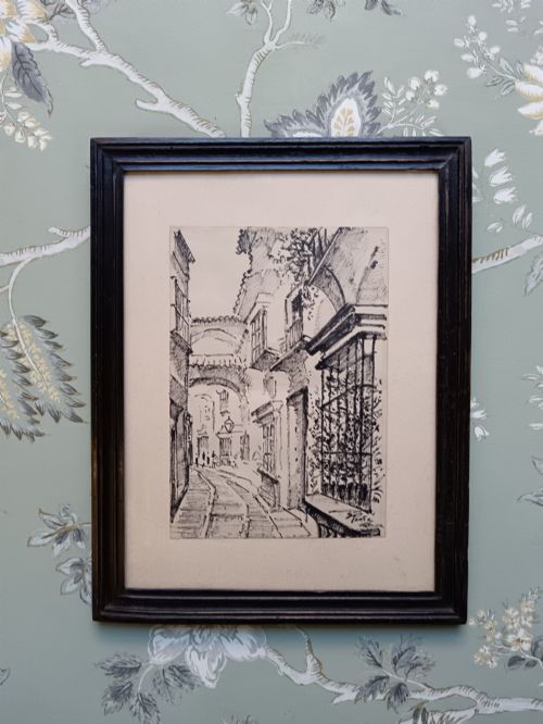 fig 2. A pair of framed mid-century black ink architectural drawings depicting narrow Spanish street scenes mounted in dark wooden frames.