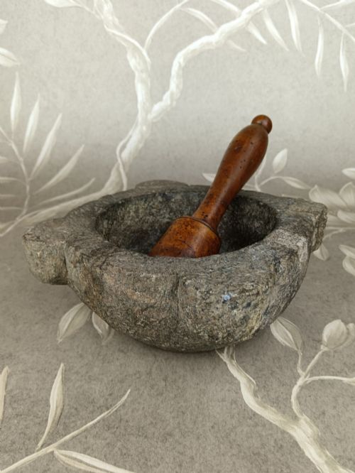 fig 1. An antique hand-carved stone mortar featuring four corner lugs, shown with a turned fruitwood pestle.