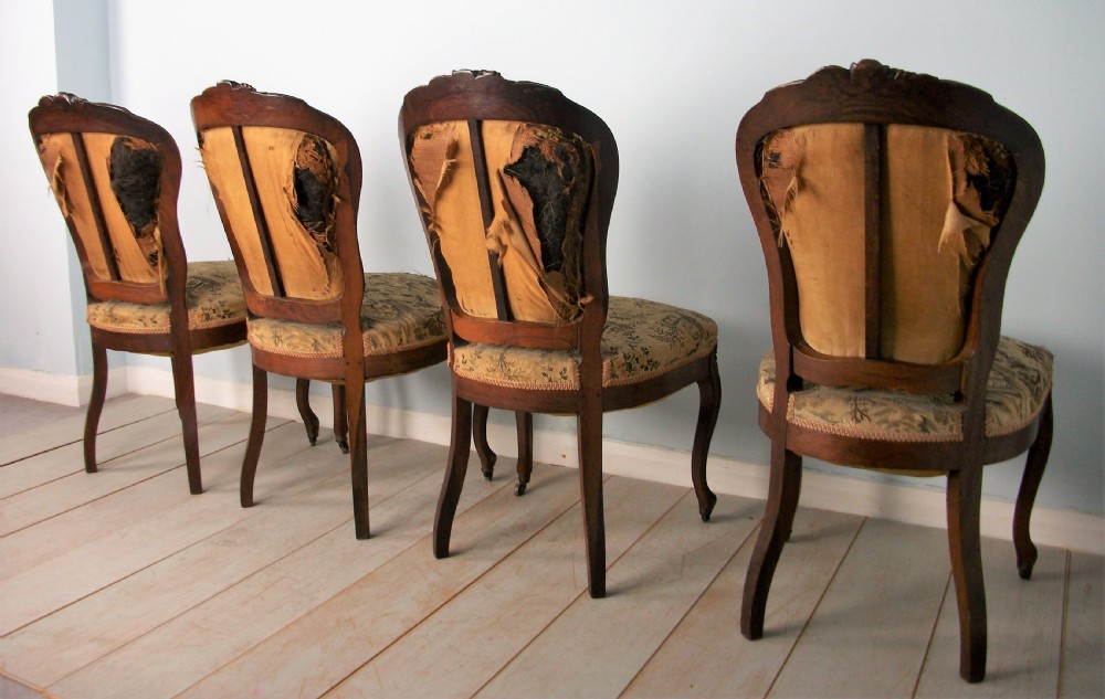 A set of four Victorian rosewood dining chairs featuring carved cartouche backs, patterned landscape upholstery, and cabriole legs on castors. View V