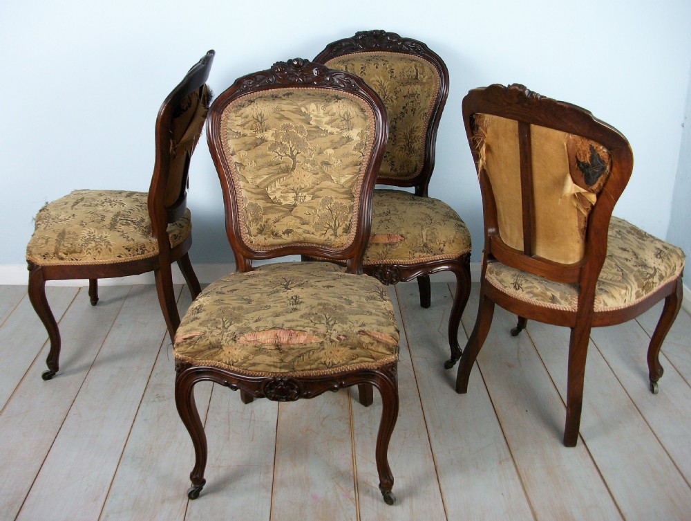 A set of four Victorian rosewood dining chairs featuring carved cartouche backs, patterned landscape upholstery, and cabriole legs on castors. View VII
