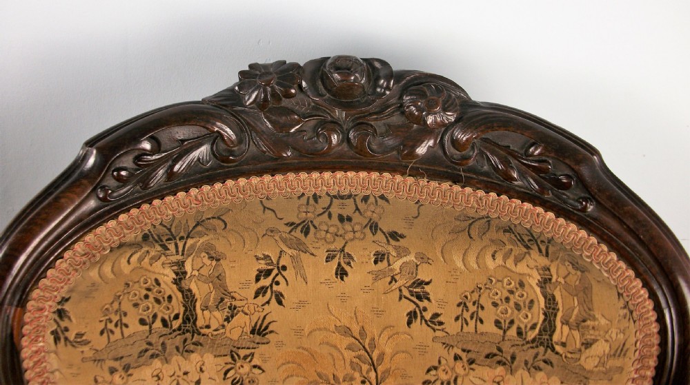 A set of four Victorian rosewood dining chairs featuring carved cartouche backs, patterned landscape upholstery, and cabriole legs on castors. View IV