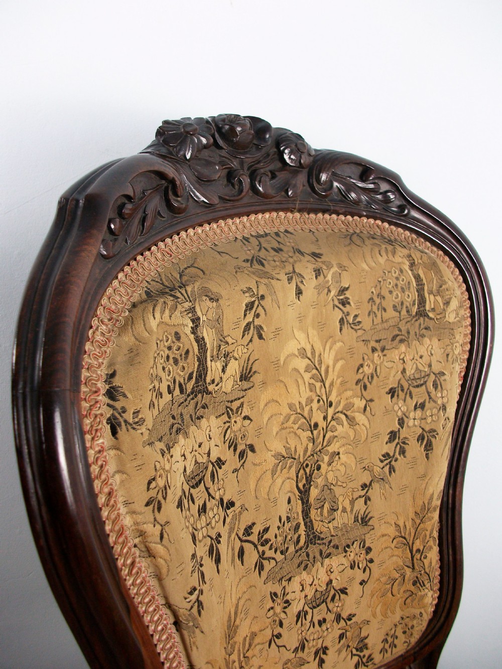 A set of four Victorian rosewood dining chairs featuring carved cartouche backs, patterned landscape upholstery, and cabriole legs on castors. View VI