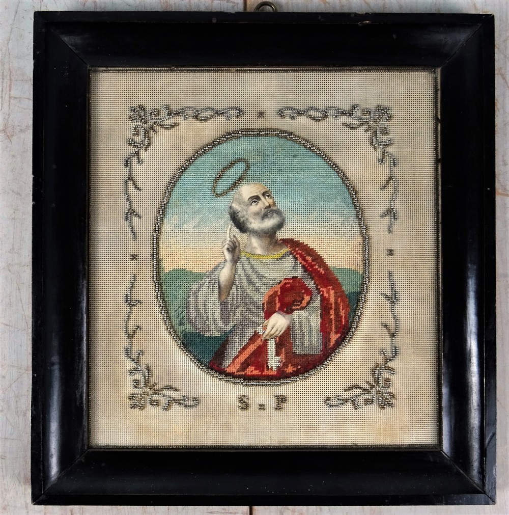 An antique Victorian needlepoint picture depicting Saint Peter holding keys within an oval beaded border with decorative corner scrollwork. View II