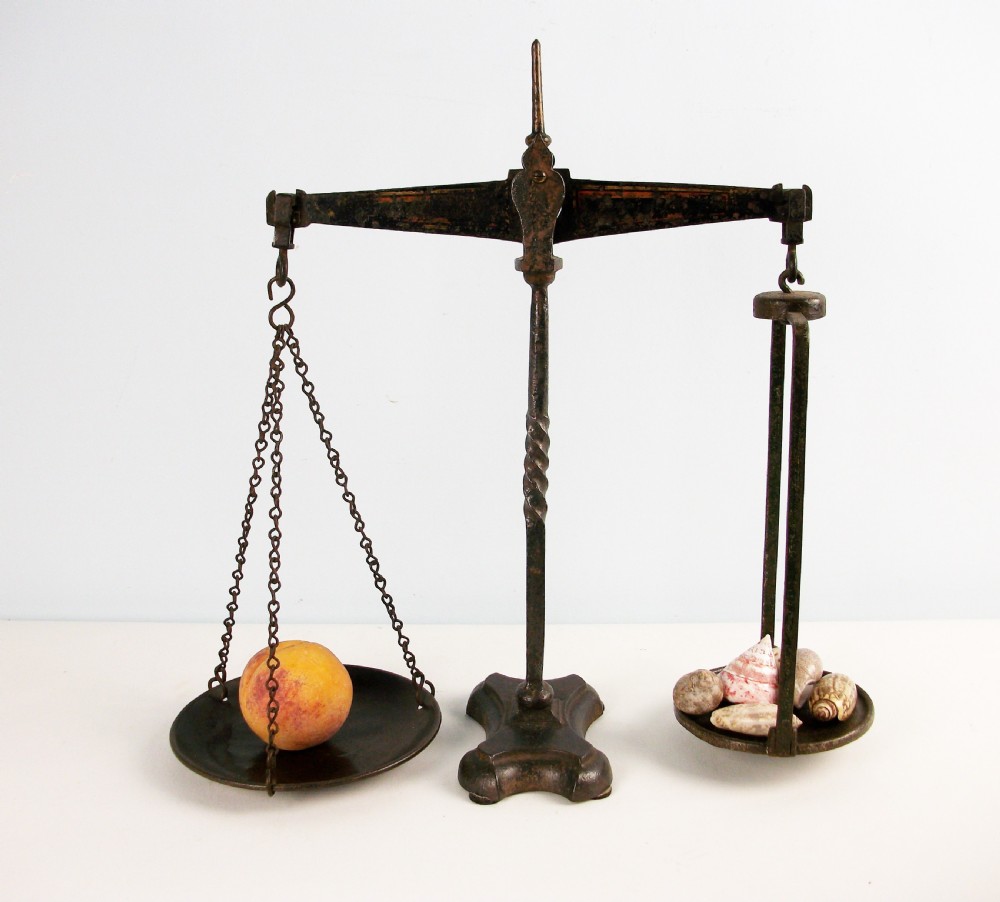 A Victorian cast iron balance scale featuring a central twisted column support, a horizontal balance beam, and two hanging metal pans.