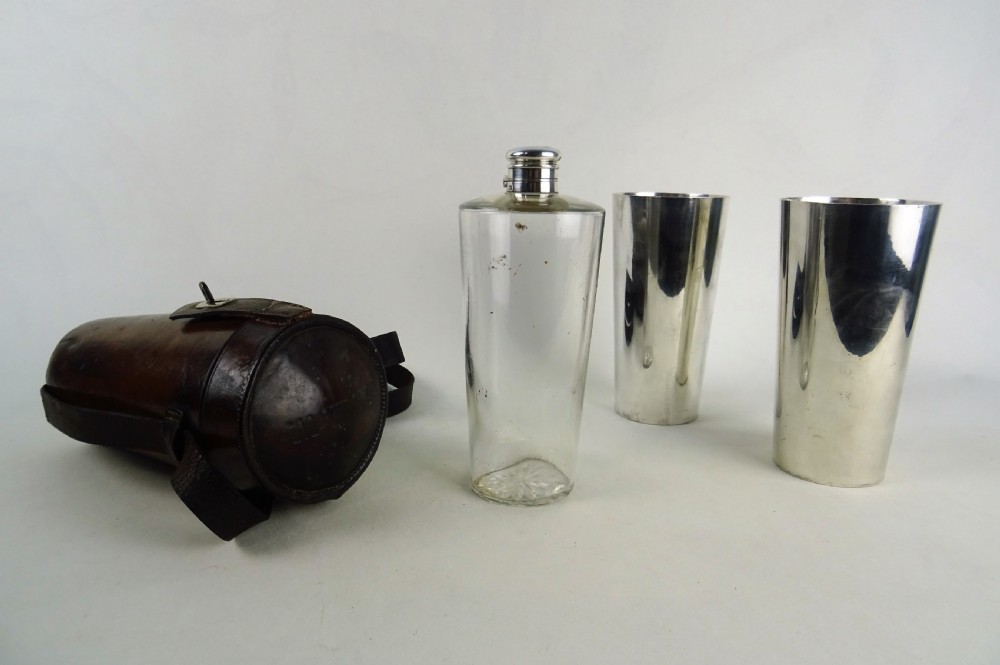 A nineteenth-century glass spirit flask encased in a dark brown leather carrying case with a leather shoulder strap and silver-toned metal cap. View V