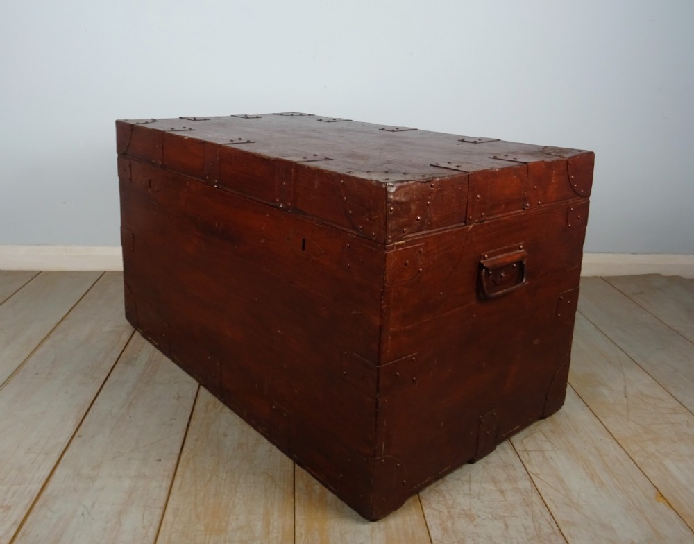 A large 19th-century dark timber campaign trunk featuring metal corner strapping, side carrying handles, and a hinged lid.