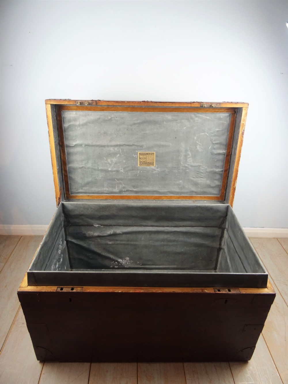 A large 19th-century dark timber campaign trunk featuring metal corner strapping, side carrying handles, and a hinged lid. View XV