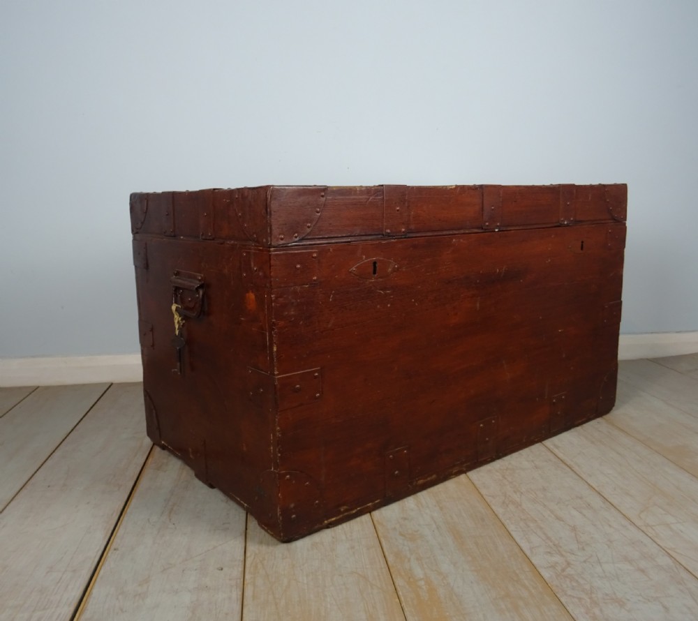 A large 19th-century dark timber campaign trunk featuring metal corner strapping, side carrying handles, and a hinged lid. View X