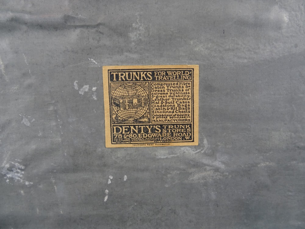 A large 19th-century dark timber campaign trunk featuring metal corner strapping, side carrying handles, and a hinged lid. View VI