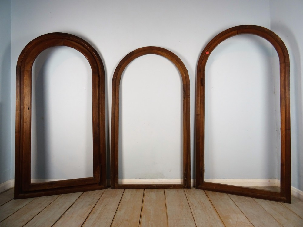 A group of three antique Italian walnut wooden door frames featuring rounded arches and moulded profiles. View XVII