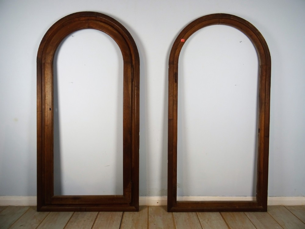 A group of three antique Italian walnut wooden door frames featuring rounded arches and moulded profiles. View V