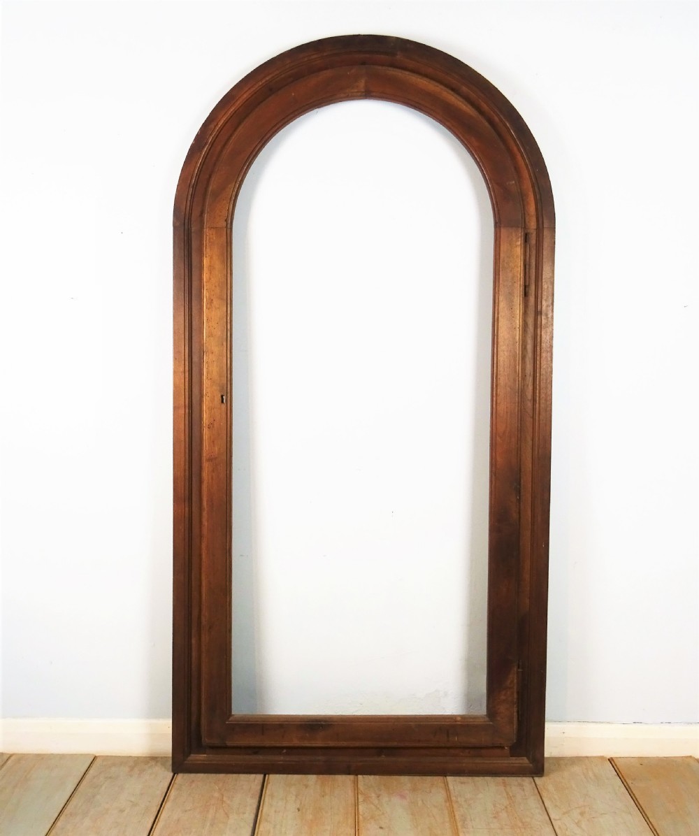 A group of three antique Italian walnut wooden door frames featuring rounded arches and moulded profiles. View VII