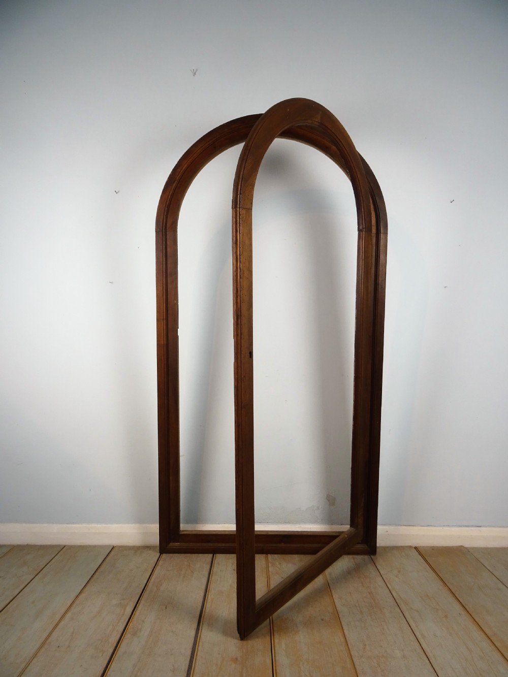 A group of three antique Italian walnut wooden door frames featuring rounded arches and moulded profiles. View XVI